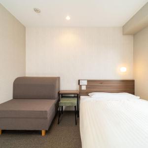 a hotel room with two beds and a chair at Super Hotel Joetsu Myoko-Eki Nishiguchi in Joetsu