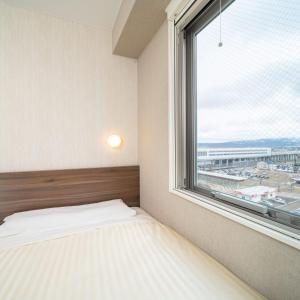 a bedroom with a bed and a large window at Super Hotel Joetsu Myoko-Eki Nishiguchi in Joetsu