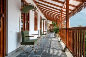 eine Veranda mit grünen Stühlen auf einem Haus in der Unterkunft Grand Hotel D'Europe in Puducherry