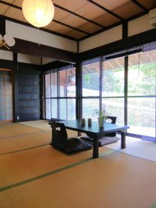 a room with a table and a couch and windows at Kumano Kodo Nagano Guesthouse in Tanabe