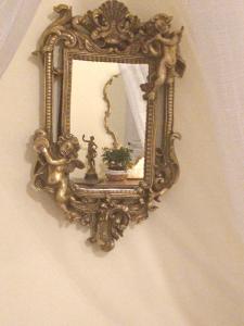 an ornate gold mirror hanging on a wall at D'oc D'or Chambre D'hôtes in Murviel