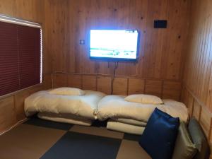 名古屋市にあるsakura.nagoyaのベッド2台と壁掛けテレビが備わる客室です。