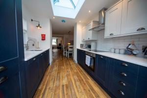 a kitchen with blue cabinets and a wooden floor at Gelly Cott in Padstow