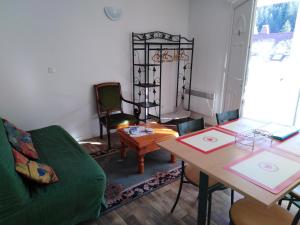 uma sala de estar com um sofá verde e uma mesa em Gite de vacances Residence La Babaute LES ROUSSES em Les Rousses