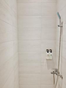 Un baño con ducha con azulejos blancos. en PlainStay Hostel, en Taipéi