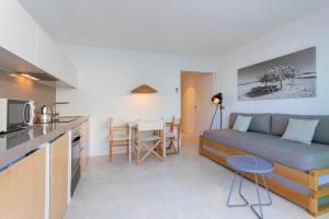 a kitchen and a living room with a couch and a table at Apartamentos Roca Plana in Es Pujols
