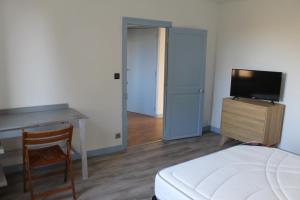 um quarto com uma cama, uma secretária e uma televisão em Les Géraniums em Cosne Cours sur Loire