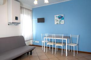 sala de estar con mesa, sillas y pared azul en Acqua Verde Appartamenti, en Peschiera del Garda