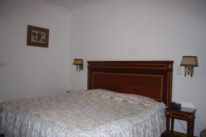 a bedroom with a bed with a wooden headboard at Hotel Sintra Jardim in Sintra