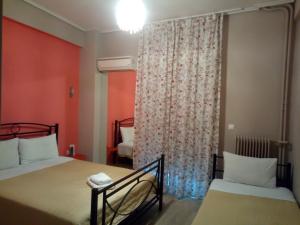 a bedroom with two beds and a window with a curtain at Zappion Hotel in Athens