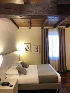 - une chambre avec un grand lit et une fenêtre dans l'établissement Hotel Boutique Antiche Mura, à Saluces