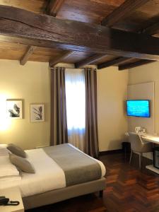 una camera con letto, scrivania e TV di Hotel Boutique Antiche Mura a Saluzzo