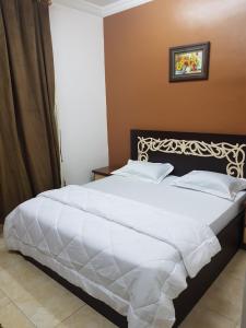 1 dormitorio con 1 cama grande con sábanas blancas en Beit Almurooj Hotel Apartment, en Salalah