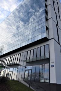 a glass building with a reflection of the sky at Apartament 807 in Warsaw