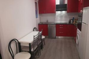 a kitchen with red cabinets and a table and chairs at Apartamento Centrico , Wifi + Desayuno in Logroño