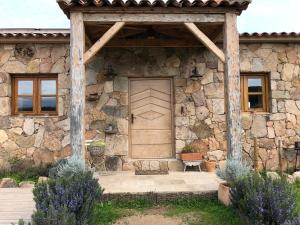 a stone house with a wooden door and a porch at Ferme de Roccapina in Sarragia