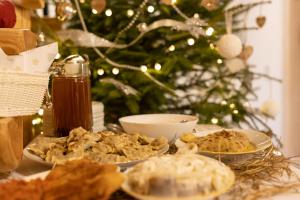 una mesa con tres platos de comida y un árbol de Navidad en Chaty Anety Domki Całoroczne en Solina