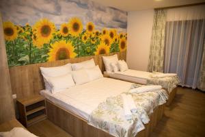 2 Betten in einem Zimmer mit einem Gemälde von Sonnenblumen in der Unterkunft Villa Bunski biser in Blagaj