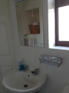 a white bathroom with a sink and a mirror at The Boat House Guesthouse in Boat of Garten