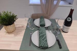 LE PETIT SAINT NICOLAS, EN PLEIN CENTRE VILLE في بون: طاولة مع أطباق وأكواب وزجاجة من النبيذ