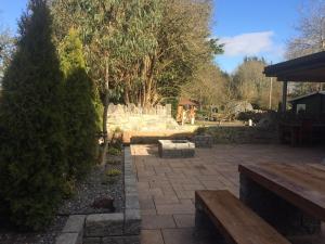 eine Terrasse mit zwei Holzbänken und Bäumen in der Unterkunft Stone Lodge B&B in Balrath