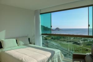 a bedroom with a bed and a view of the ocean at Sophia II Residence Inn in Arraial do Cabo