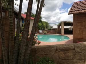 a swimming pool in a yard with palm trees at Jozini Lebombo Lodge in Jozini