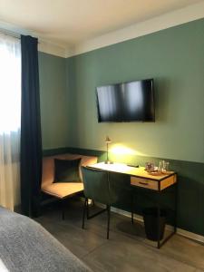 a bedroom with a desk and a television on the wall at Pension Mariposa in Weimar