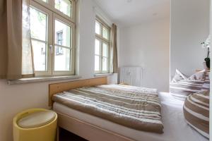 ein Schlafzimmer mit einem Bett und zwei Fenstern in der Unterkunft Ferienwohnung am Goethepark im Leipziger Neuseenland in Leipzig