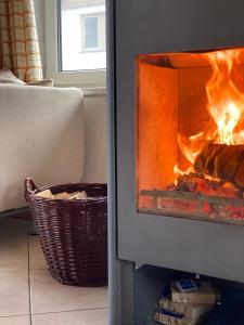 a fire burns in a fireplace with a basket at Chalet 48 in Hermagor