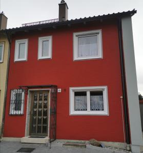 una casa roja con una puerta y dos ventanas en Ferienhaus CasaNoWa en Kaufbeuren