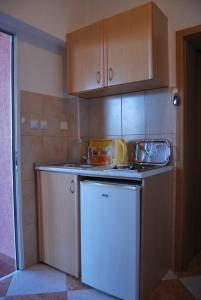 a kitchen with a white refrigerator and wooden cabinets at Omega Apartments in Ulcinj