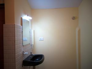 THE ENCHANTING NEST في Borim: حمام مع حوض أسود ومرآة