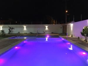 a swimming pool lit up at night with purple lights at Mansão Beberibe in Beberibe