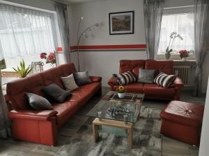 una sala de estar con sofás de cuero rojo y una mesa. en Ferienhaus CasaNoWa en Kaufbeuren