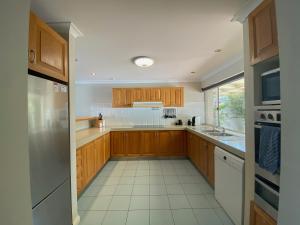 a kitchen with wooden cabinets and a white tile floor at Waterside Canal Dreams in Mandurah