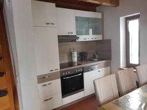 uma cozinha com armários brancos e um forno com placa de fogão em Ferienhaus Bayerischer Wald em Regen