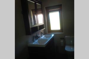 ein Bad mit einem Waschbecken, einem Fenster und einem WC in der Unterkunft Chalet ENTERO CONFORT in Ribeira