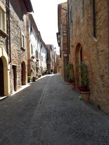 een lege geplaveide straat in een steegje tussen gebouwen bij Dinas House Tuscany Holidays in Terricciola