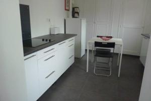 uma cozinha branca com uma mesa e um frigorífico branco em L'Oseraie em Moisenay
