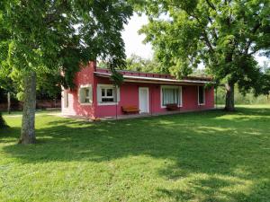 een rood huis in een tuin met bomen bij La Rosadita Casa de Campo in Chascomús