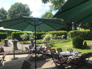 a patio with a table and chairs under a green umbrella at Gut Merödgen in Inden