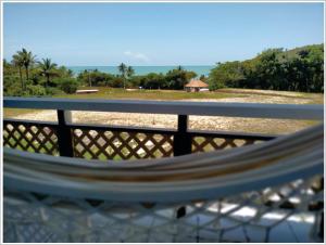 a bench with a view of a beach and a fence at Pousada das Falésias in Prado