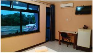 Zimmer mit einem Schreibtisch und einem Fenster mit Blick auf ein Boot. in der Unterkunft Pousada das Falésias in Prado