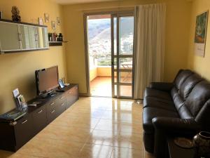 a living room with a black leather couch and a television at Vivienda Vacacional Balcón de La Villa in San Sebastián de la Gomera