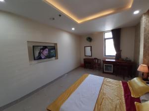 1 dormitorio con TV en una pared blanca en Hotel Phú Sĩ, en Ho Chi Minh