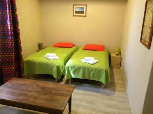 2 letti in una camera con lenzuola verdi e cuscini rossi di La maison du vigneron a Ternand