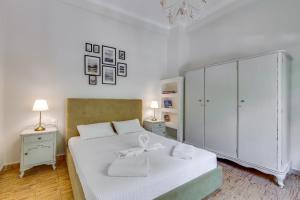 a bedroom with a white bed and a white cabinet at Samouil Apartment, 40 meters from the beach in Chania Town