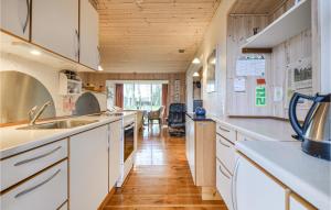 Il comprend une cuisine avec des placards blancs et un plafond en bois. dans l'établissement Cozy Home In Ebeltoft With Kitchen, à Ebeltoft