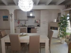 uma cozinha com uma mesa e cadeiras brancas e um candelabro em villa relax sul mare em Gallipoli